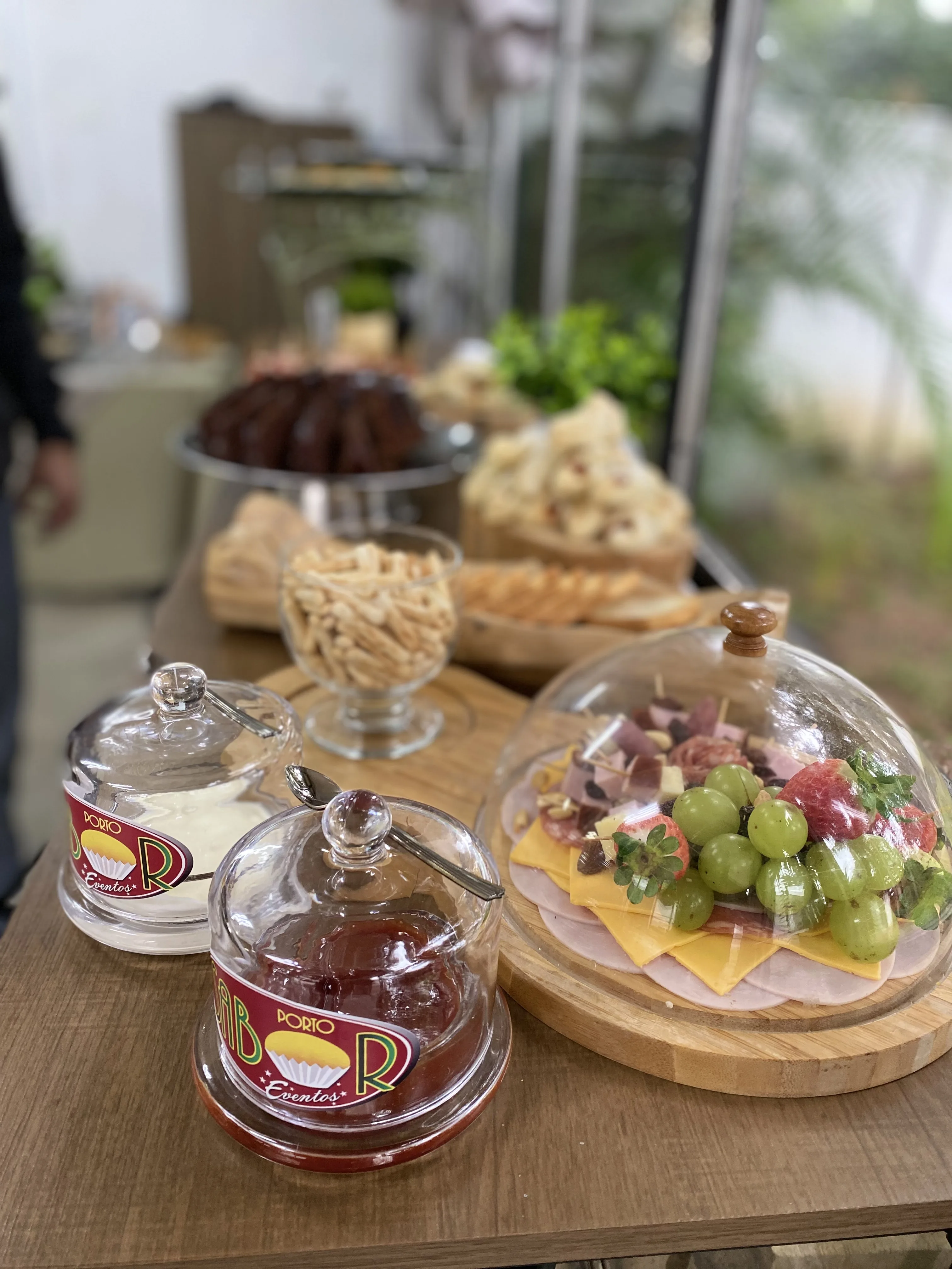 Mesa de evento Porto Sabor com doces, frutas, chá e itens servidos em tábuas.
