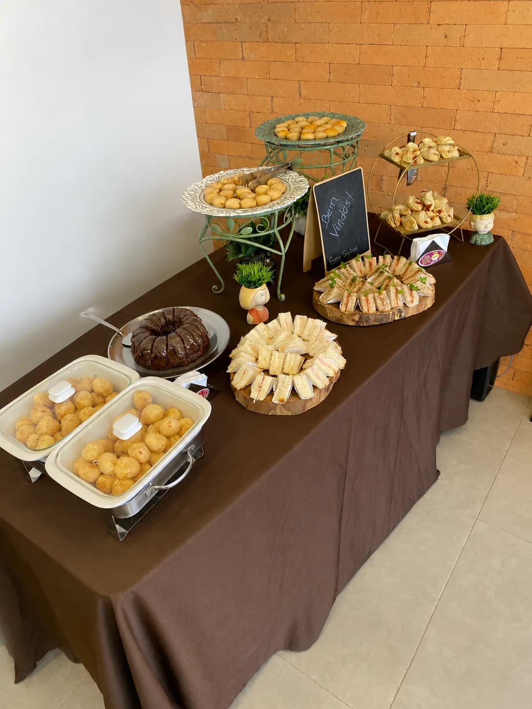 Mesa de catering Porto Sabor com salgados, doces, flores e café para evento.
