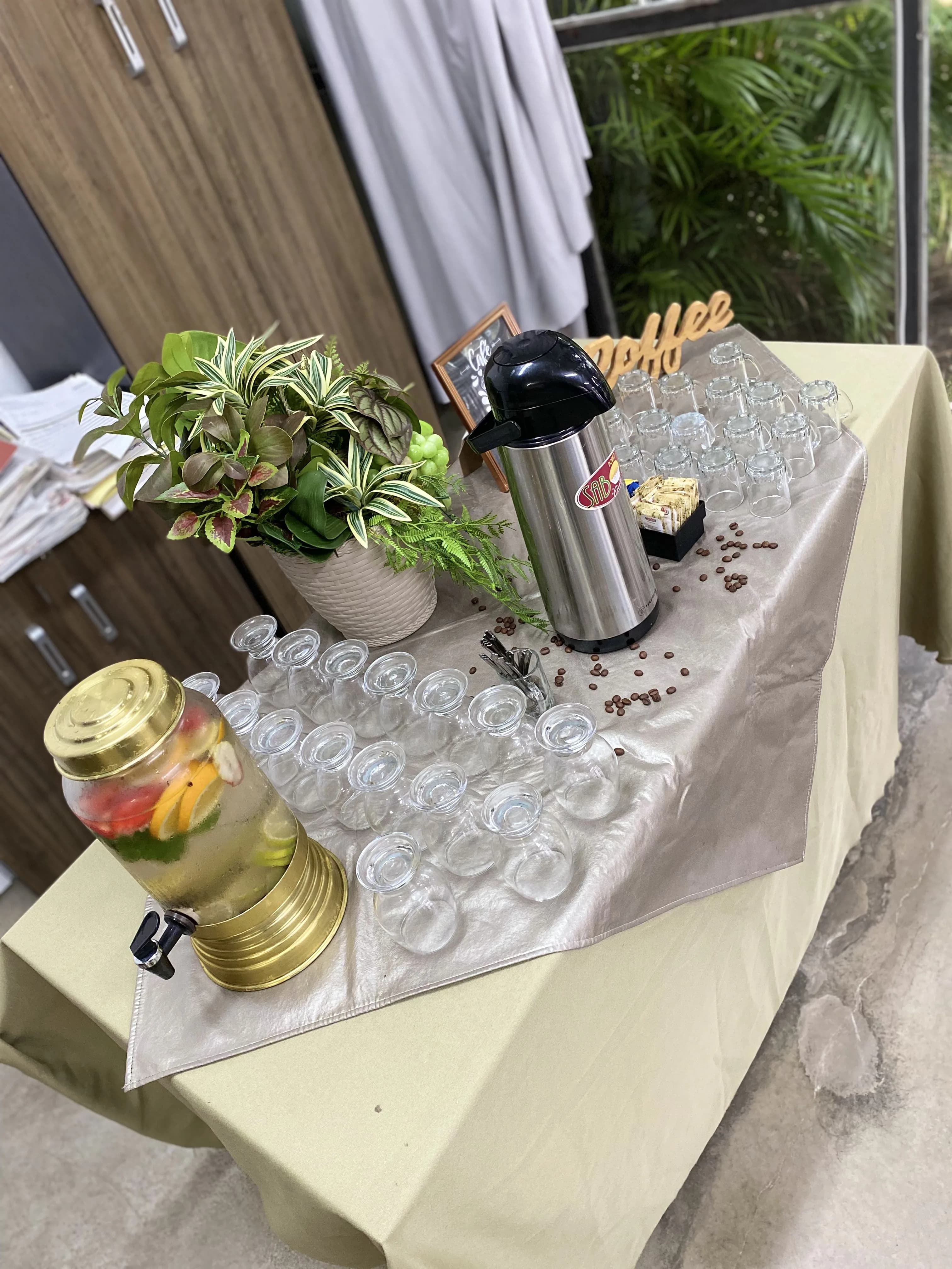 Ilha de café Porto Sabor com garrafa térmica, copos e água aromatizada para evento.